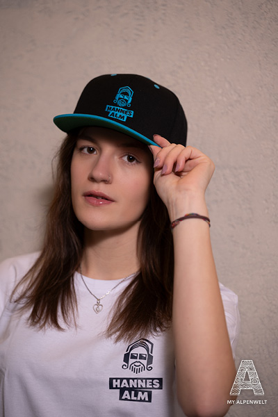 Black baseball cap with blue Hannes Alm logo and blue accents