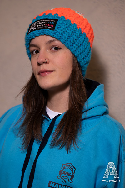 blue-orange-white wool hat with white pom-pom & Alpenwelt, Susi Alm, and Hannes Alm logo patch